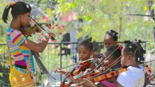 La profesora de música Anne Ludia dando clases de violín a niñas de Haití.