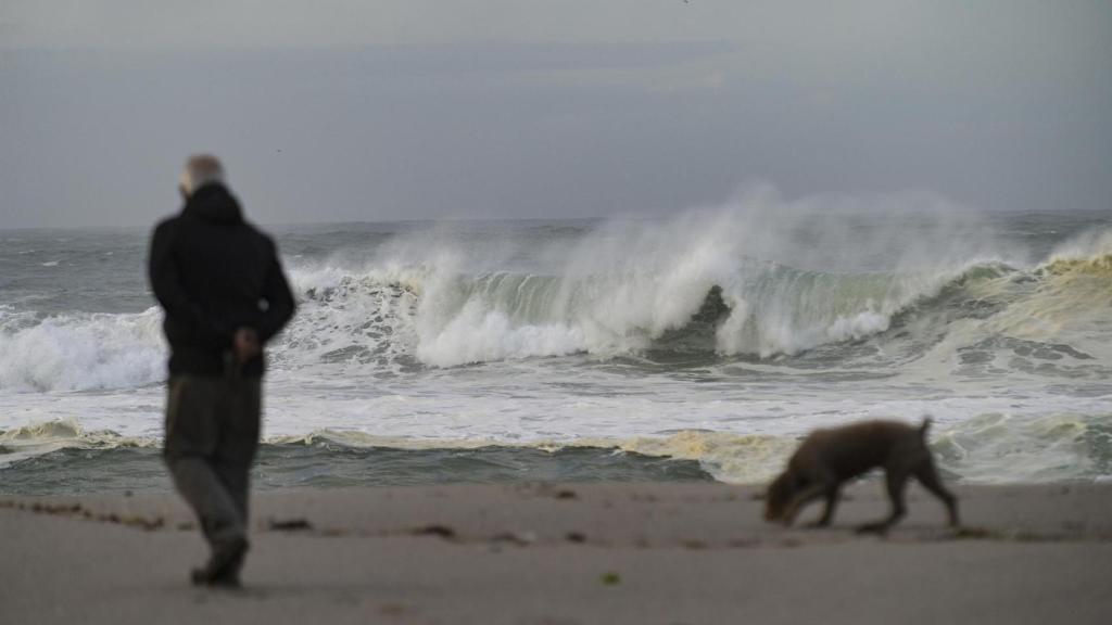 Un hombre paseando por la playa cuando hay fuerte oleaje.