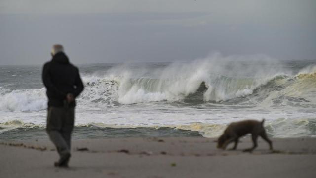 Un hombre paseando por la playa cuando hay fuerte oleaje.