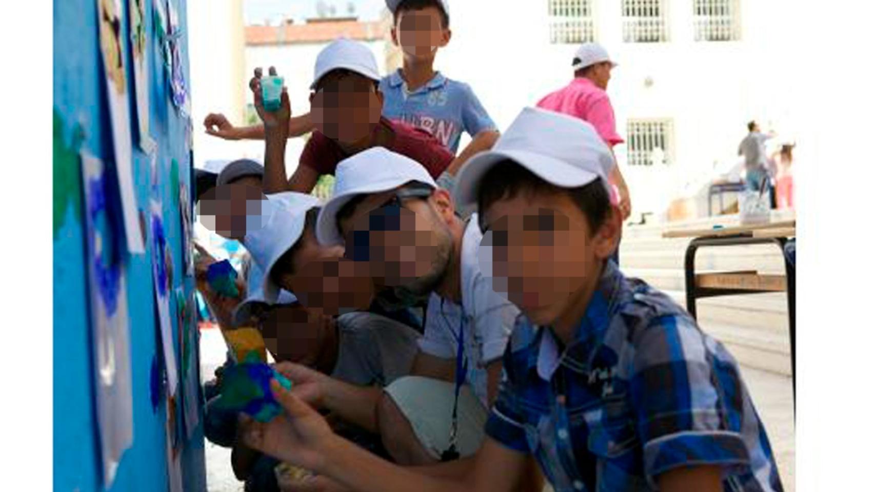 Menores marroquíes realizando un mural junto a un tutor en el Centro Social Assadaka de Tánger.