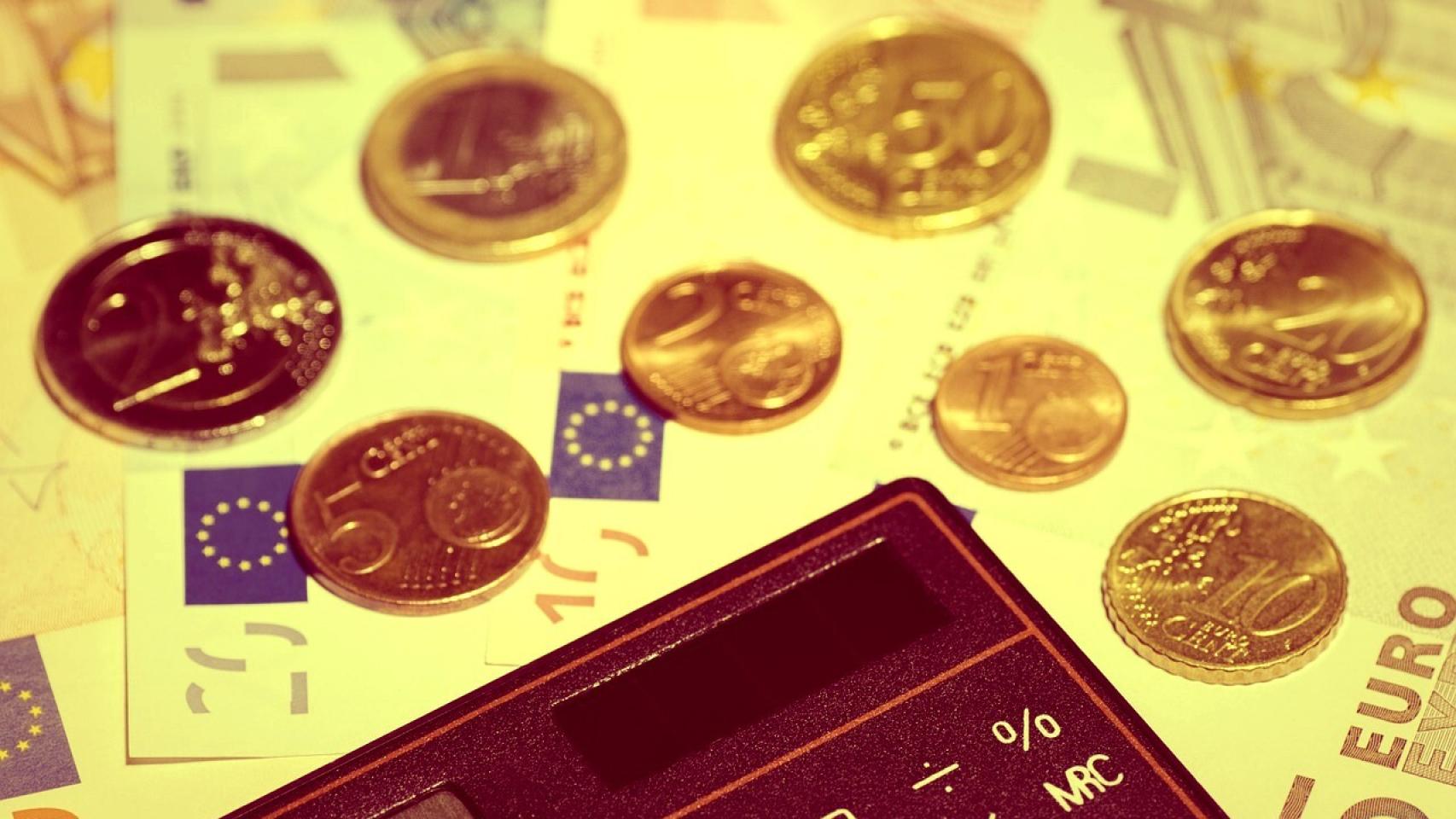 Billetes y monedas de euro junto a una calculadora.