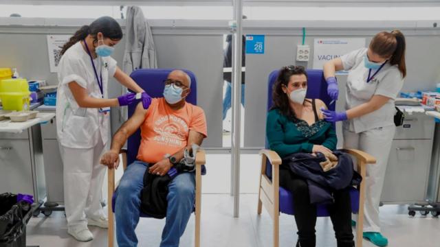 Dos personas recibiendo sendas dosis de la vacuna en el Hospital Isabel Zendal de Madrid.