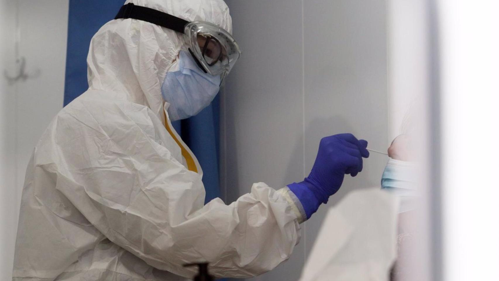 Una sanitario realiza una prueba PCR a un paciente.