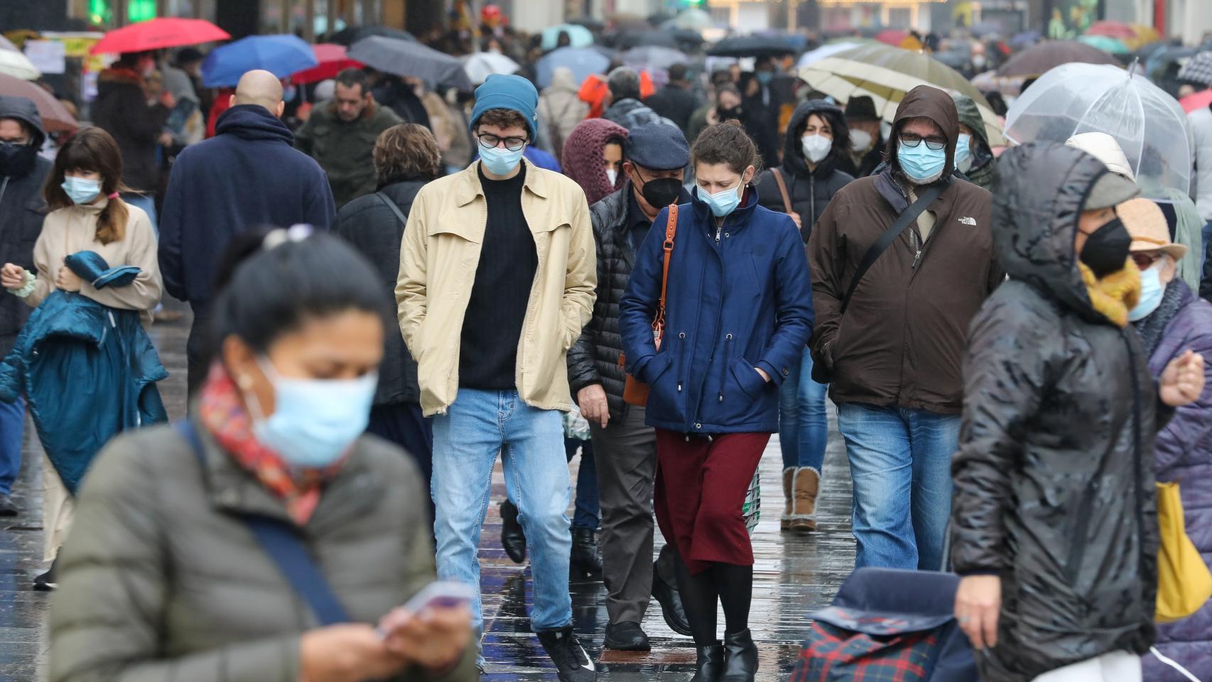 Transeúntes con mascarilla por las calles de Madrid.