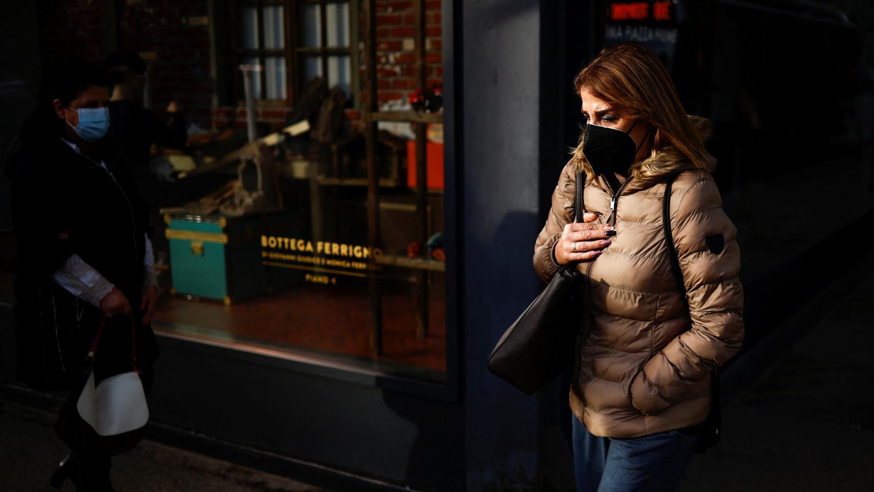 Una mujer con mascarilla pasea por las calles de Roma, Italia.
