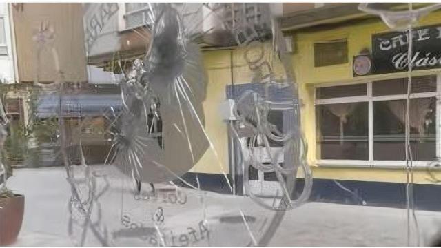 La cristalera de la barbería rota tras el intento de robo.