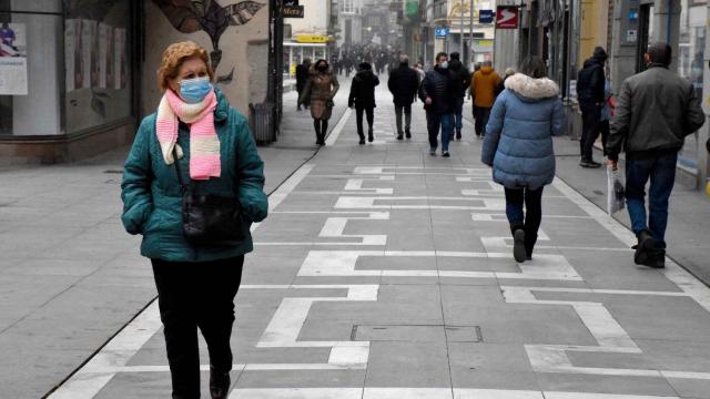 Una mujer lleva una mascarilla en una vía pública.