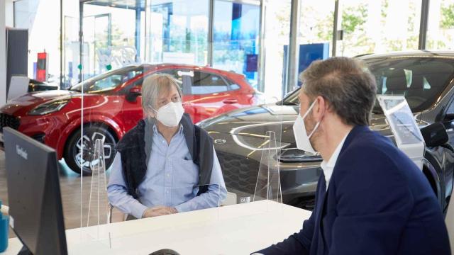Un cliente habla con un vendedor de coches en un concesionario.
