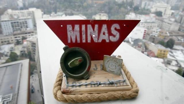 Vista de una maqueta con partes de una mina antipersona y una señal de advertencia.