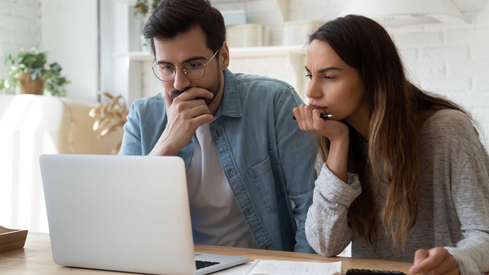 Dos jóvenes buscando vivienda en un ordenador.