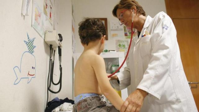 Una pediatra atiende a un niño en su consulta.
