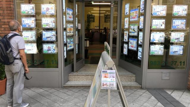 Un hombre ojea los carteles de venta de viviendas en el escaparate de una inmobiliaria