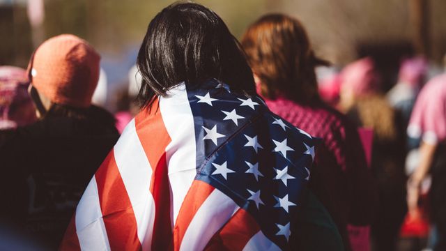 Una mujer latina lleva la bandera de Estados Unidos durante una concentración. Foto: Josh Johnson / Unsplash.