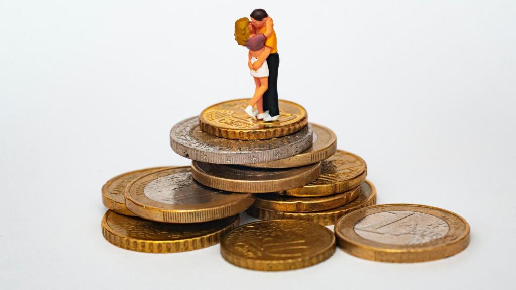 Composición de dos amantes sobre una pila de monedas de euro.