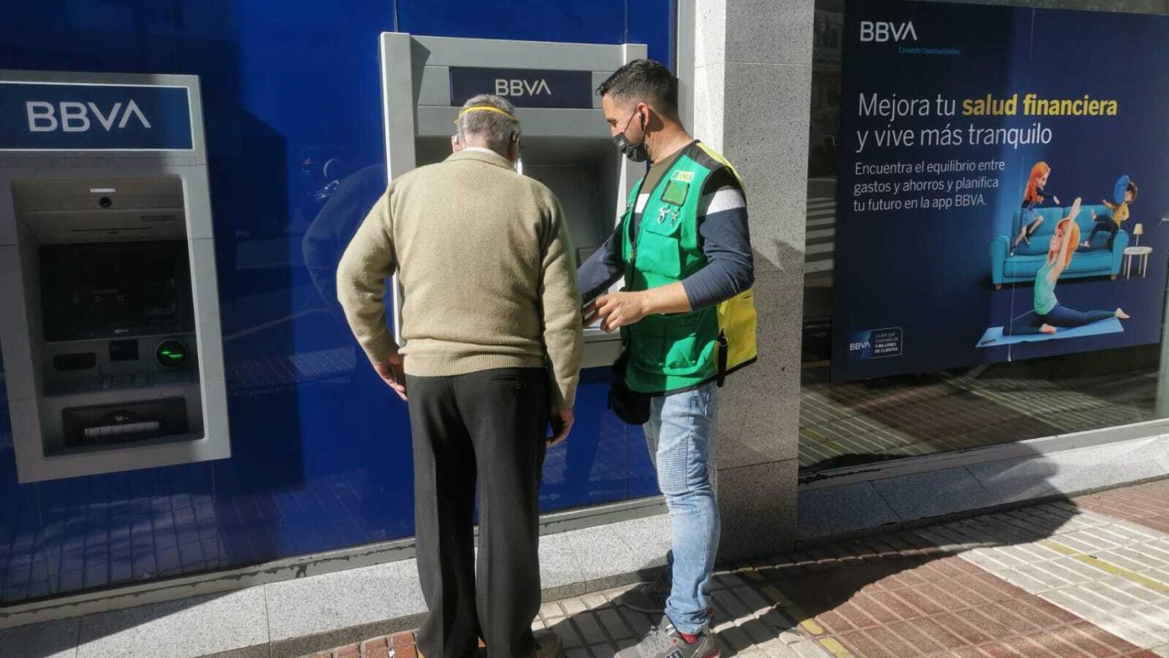 Juanma ayudando a un señor a realizar sus operaciones en el banco.