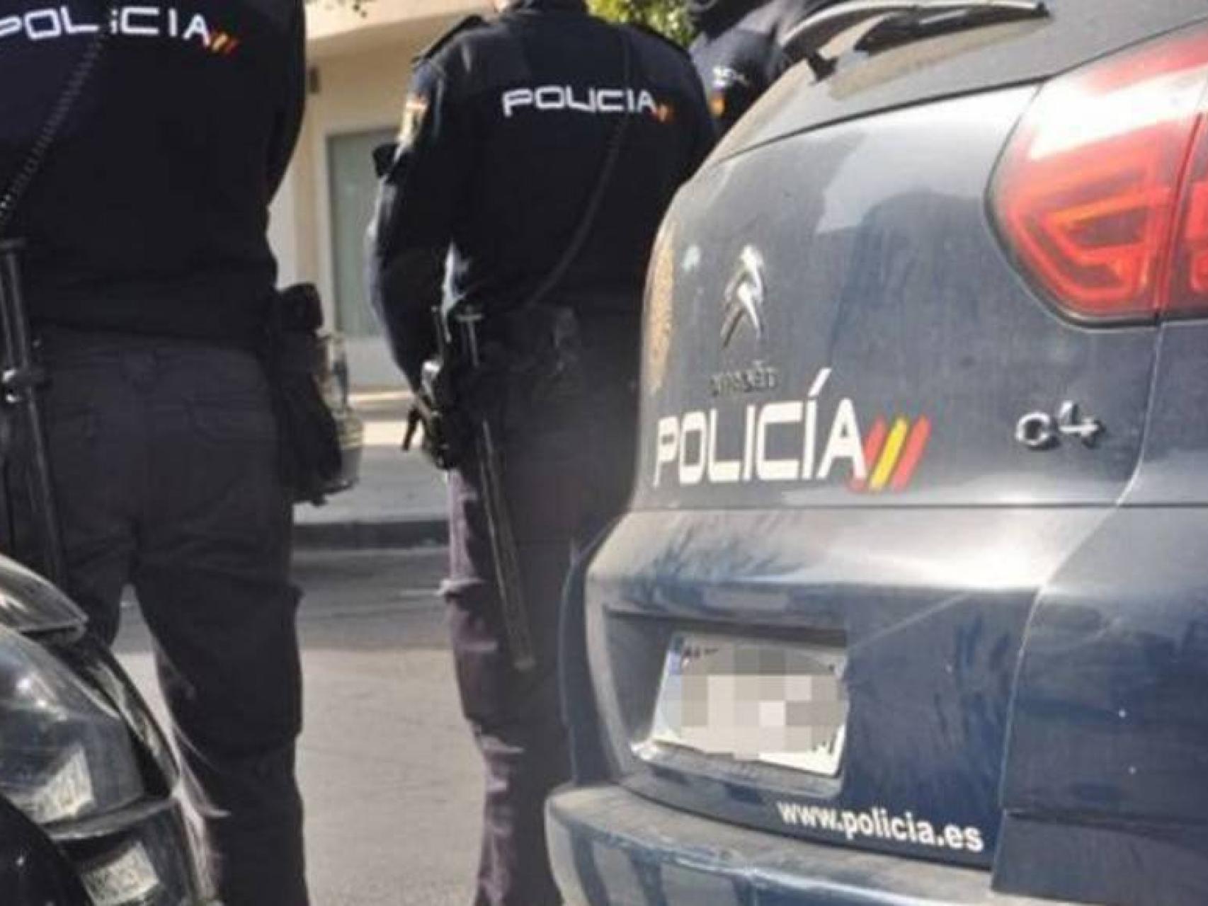 Dos policías nacionales junto a los vehículos