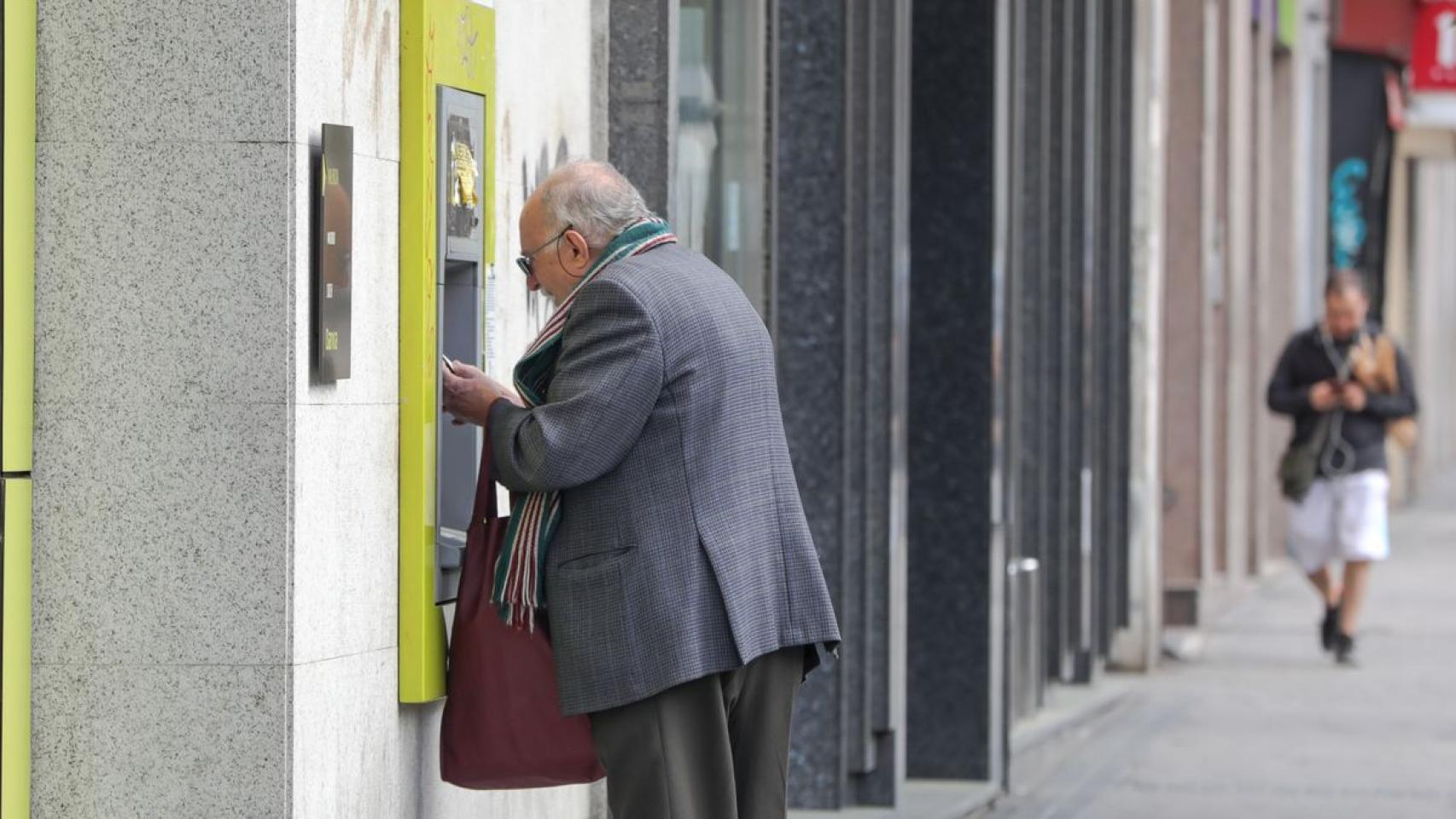 Un jubilado retira dinero en un cajero.
