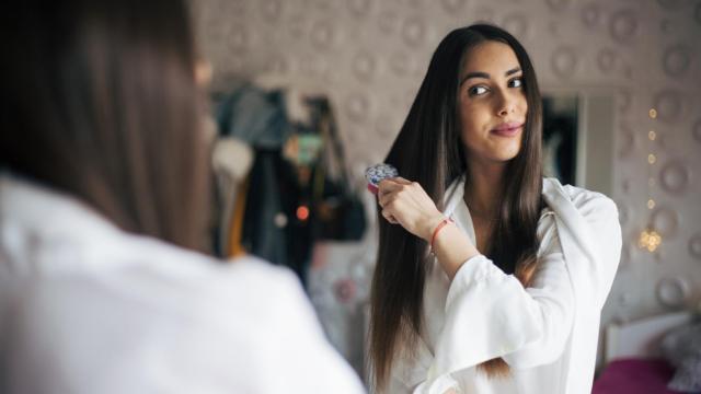 Una mujer se alisa el pelo en casa.