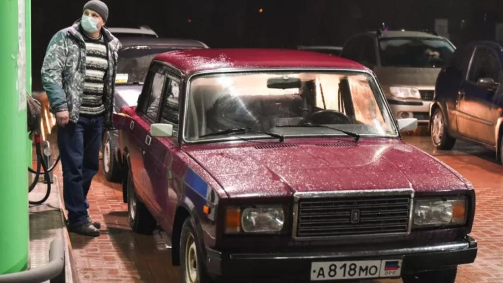 Un hombre para a poner gasolina antes de marcharse de Donetsk.