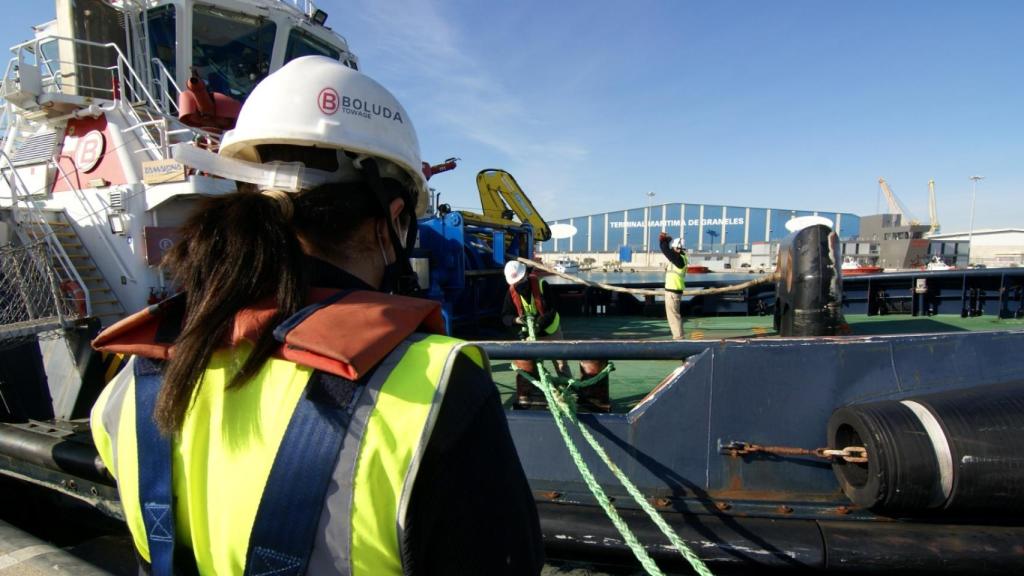 Una mujer frente a un barco mercante.