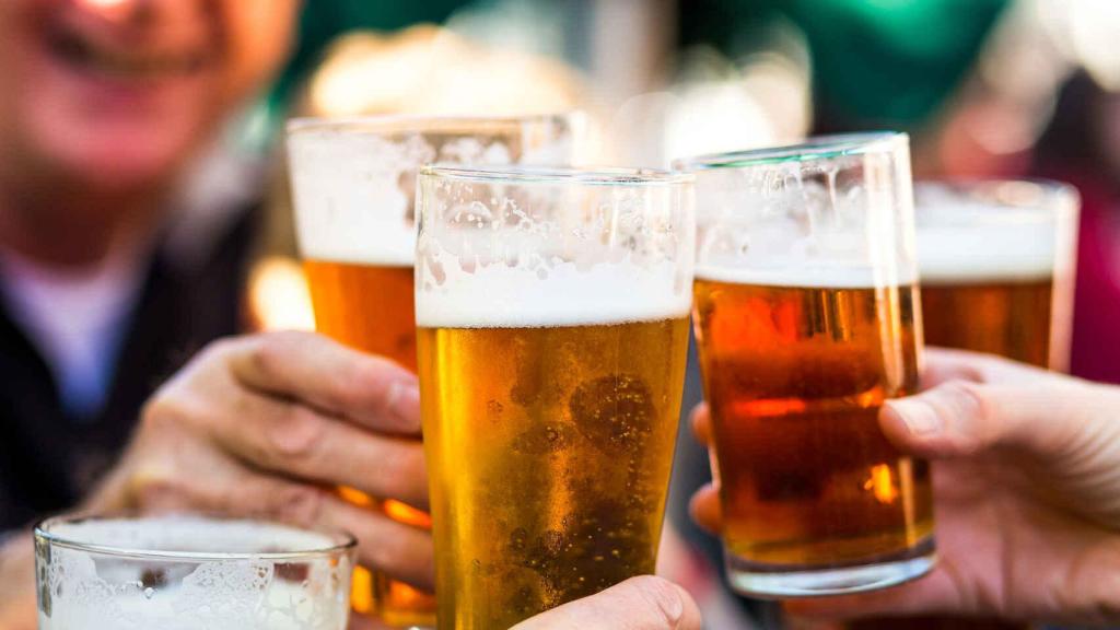Varias personas brindando con unos vasos de cerveza.