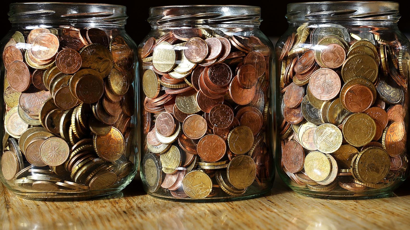 Varios botes de cristal llenos de monedas de euro.