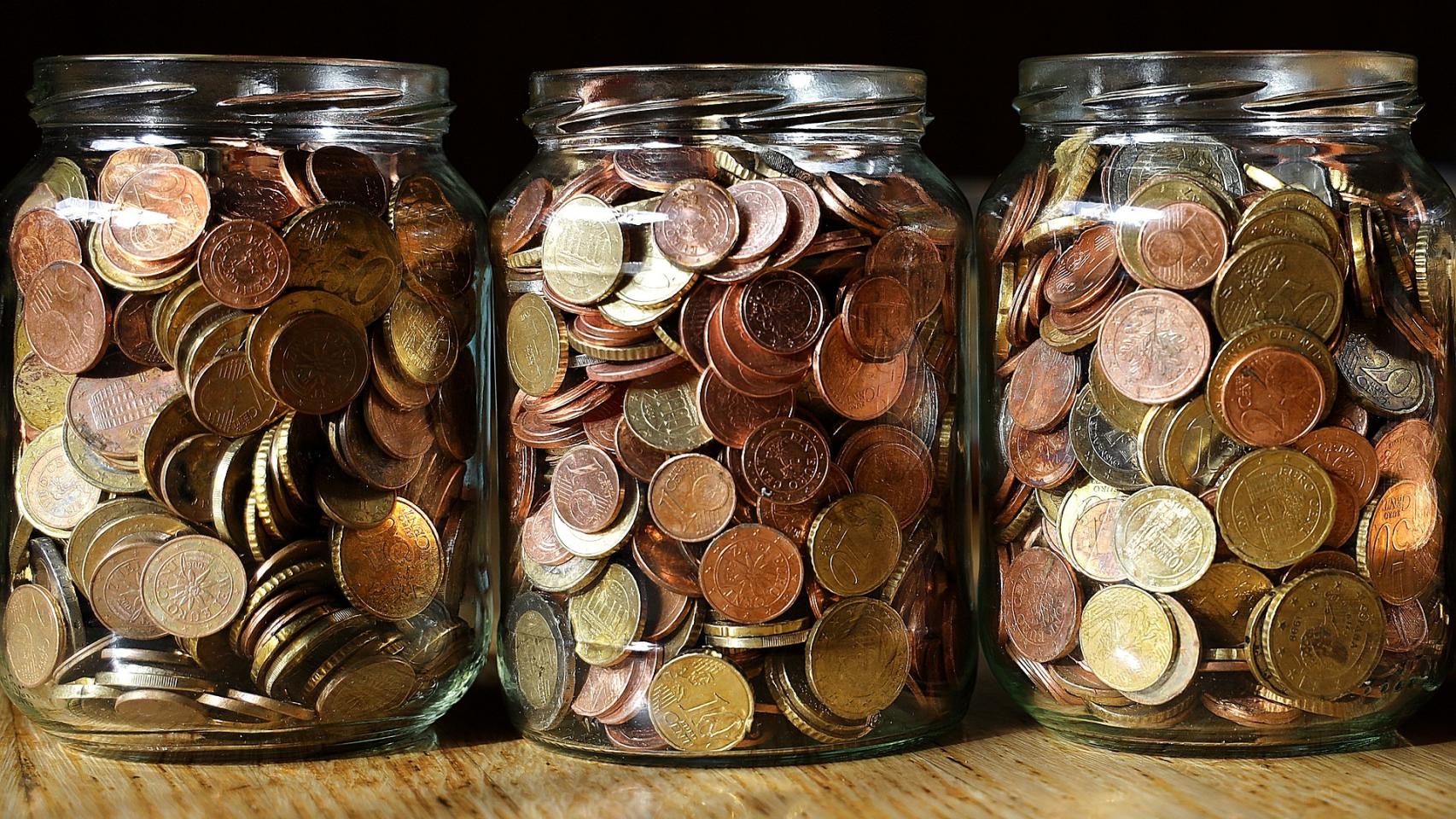 Varios botes de cristal llenos de monedas de euro.