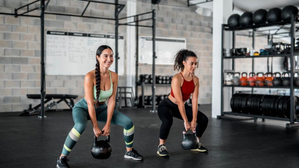 Mujeres haciendo deporte con kettlebells en el gym.