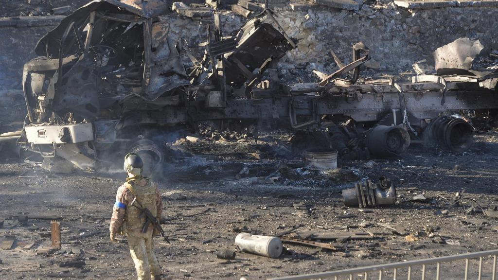 Un militar ucraniano se encuentra cerca de un vehículo carbonizado después de los combates nocturnos en Kiev.