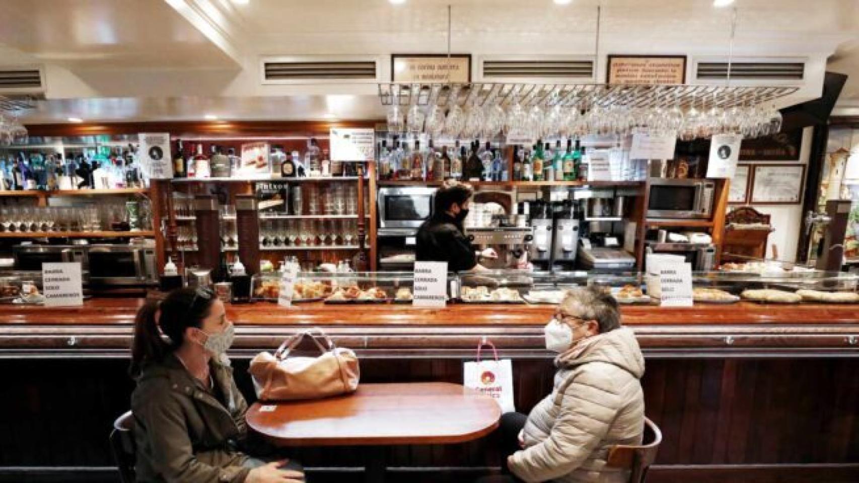 Dos personas en la barra de un bar sentadas y con mascarilla. Efe