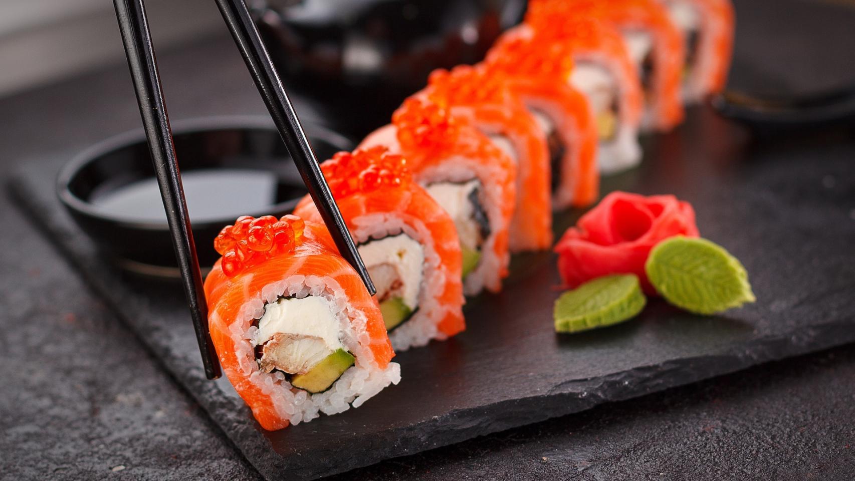 Una persona coge sushi con palillos.