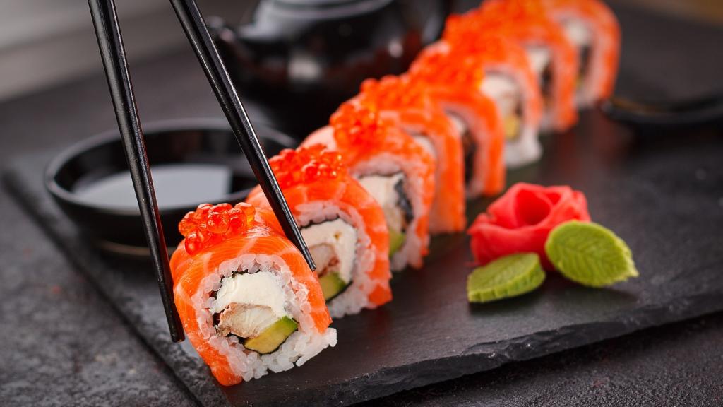 Una persona coge sushi con palillos.