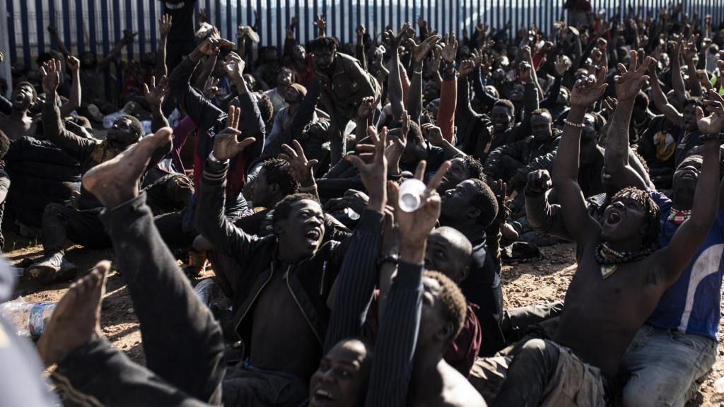 Unos 500 migrantes hacen el signo de la victoria tras saltar la valla de Melilla.