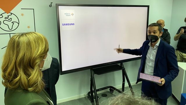 La ministra atiende frente a la pizarra digital de Samsung en el Aula de Futuro de Valencia.