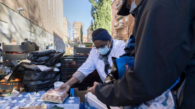 Una mujer recoge comida en una cola del hambre.