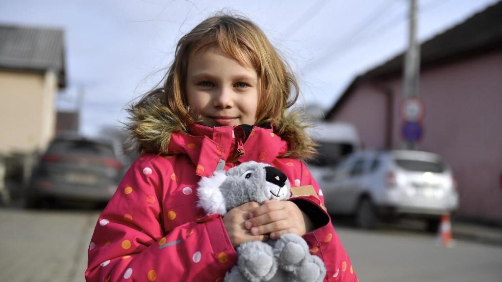 Una niña refugiada sostiene su peluche de koala