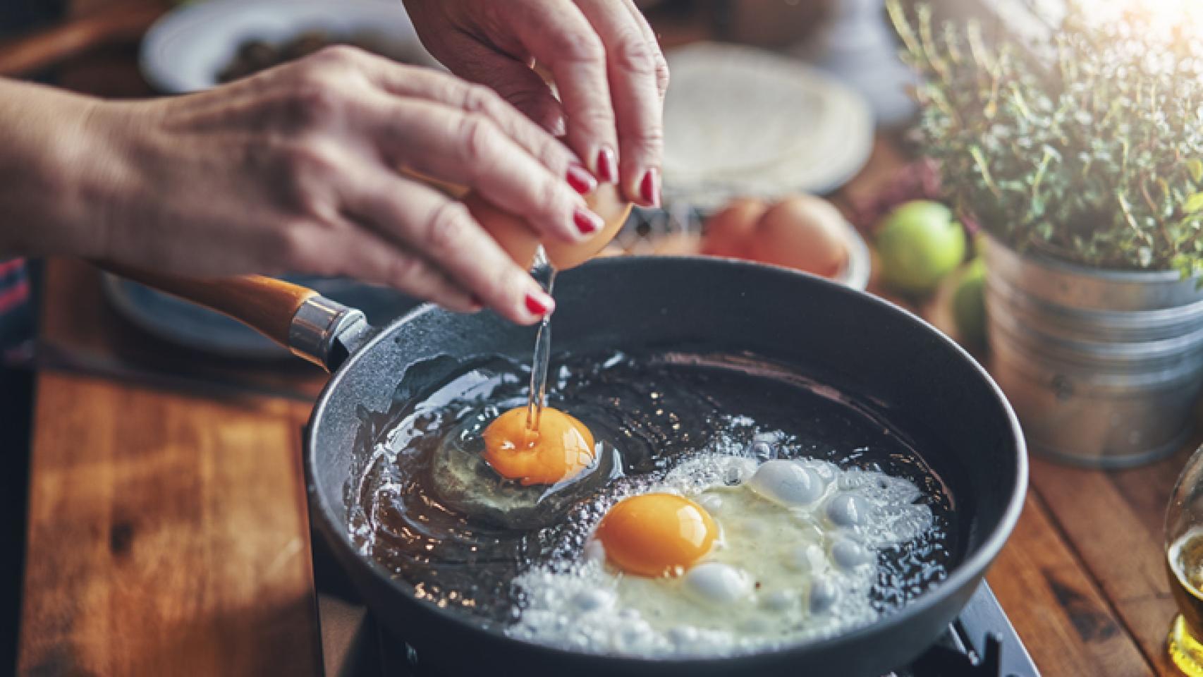 Una mujer friendo huevos.