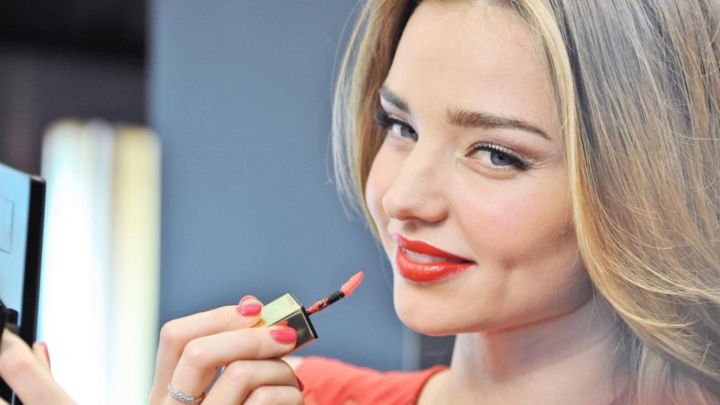 La actriz Miranda Kerr maquillándose los labios.