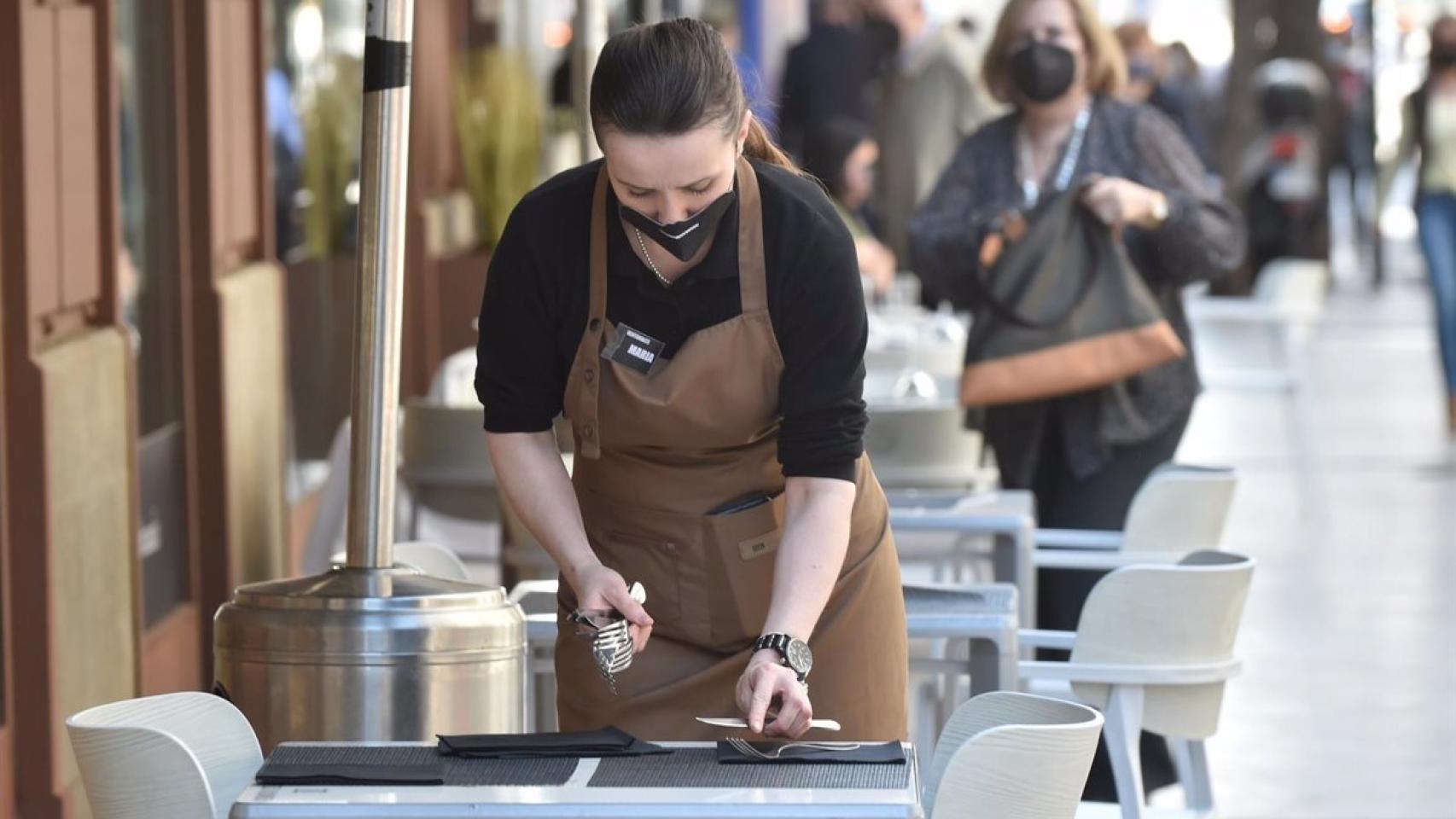 Una camarera prepara una mesa en un restaurante de Málaga.