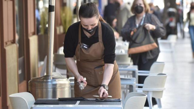 Una camarera prepara una mesa en un restaurante de Málaga.