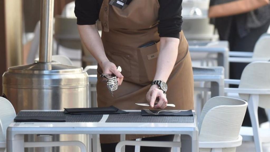 Una camarera prepara una mesa en un restaurante de Málaga.