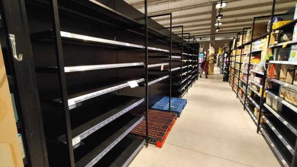 Una mujer se asoma al pasillo de la leche en un Carrefour, cuyas estanterías están vacías.