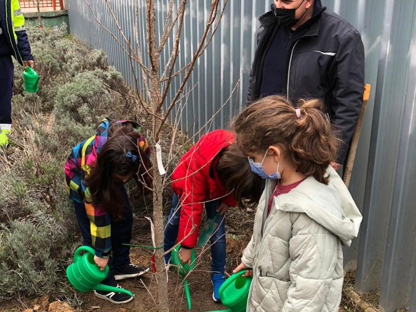 Varios pequeños riegan árboles en el centro escolar Elvira Lindo de Arroyo de la Encomienda