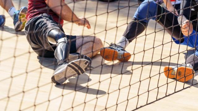 Varios deportistas juegan a voleibol adaptado.