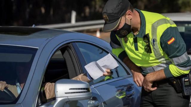 Un guardia civil revisando los papeles de un conductor.