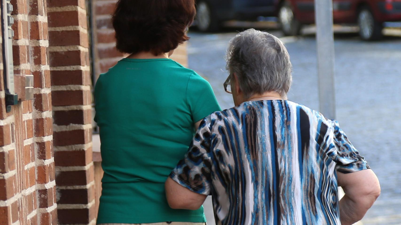 Una persona mayor camina acompañada por una calle de Segovia