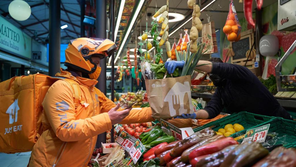 Un repartidor de Just Eat recogiendo la compra en un mercado municipal.