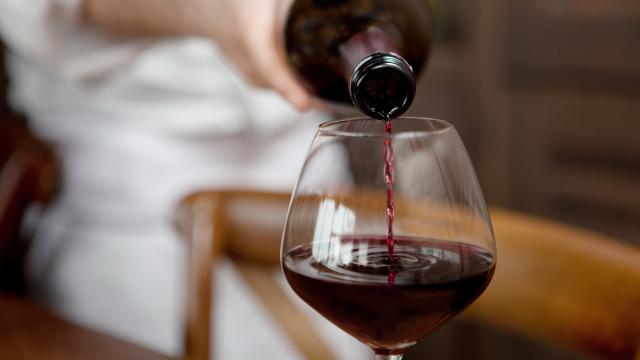 Un camarero sirviendo una copa de vino.