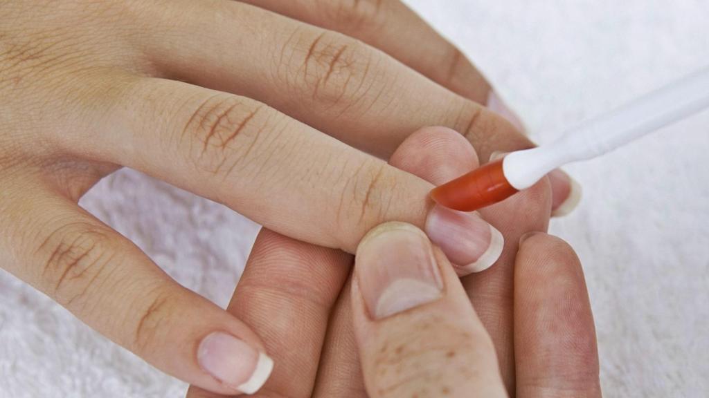 Modelo aplicándose un producto en las uñas.