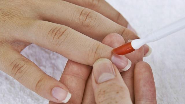 Modelo aplicándose un producto en las uñas.